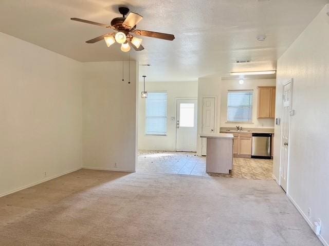 unfurnished living room featuring baseboards, a sink, ceiling fan, and light carpet