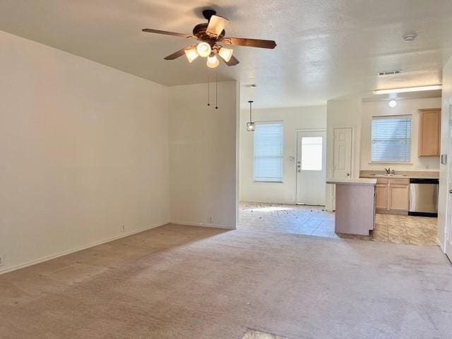 unfurnished living room featuring light colored carpet, a ceiling fan, a sink, and baseboards
