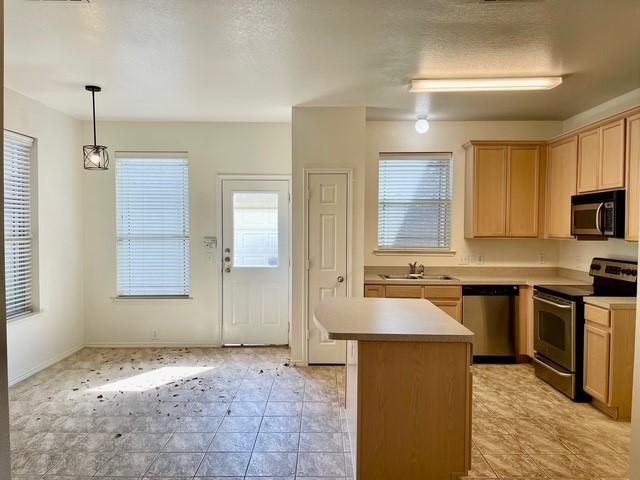 kitchen with light tile patterned flooring, appliances with stainless steel finishes, a sink, light brown cabinets, and light countertops