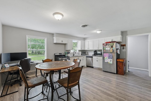 kitchen featuring visible vents, a sink, appliances with stainless steel finishes, and white cabinets