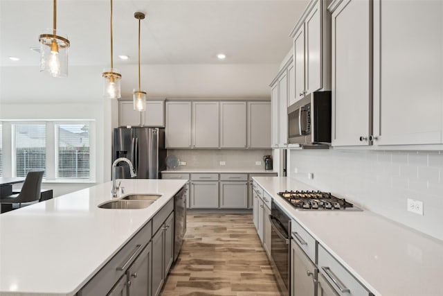 kitchen with appliances with stainless steel finishes, tasteful backsplash, a sink, gray cabinetry, and recessed lighting