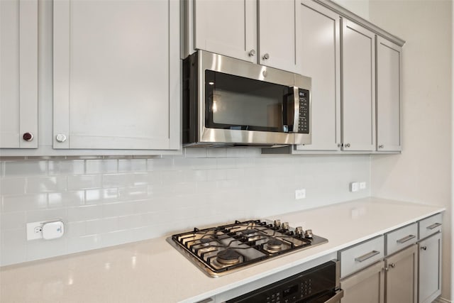 kitchen featuring light countertops, tasteful backsplash, stainless steel appliances, and gray cabinetry