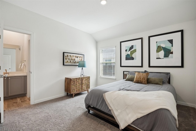 carpeted bedroom featuring baseboards, ensuite bath, and lofted ceiling