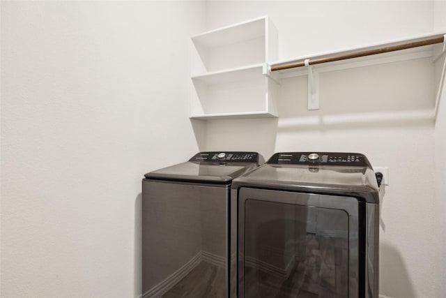 clothes washing area with laundry area, baseboards, wood finished floors, and washing machine and clothes dryer
