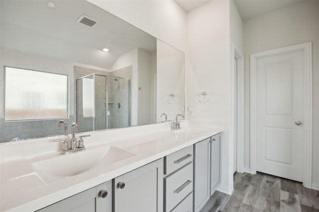 bathroom with double vanity, visible vents, a sink, and a stall shower