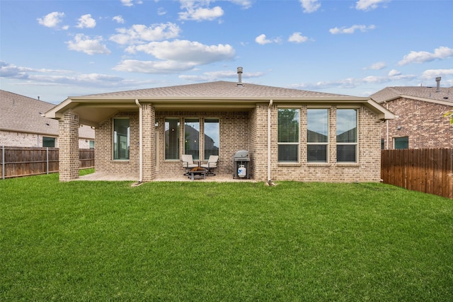 rear view of property with a lawn, brick siding, a fenced backyard, and a patio area