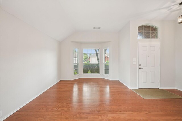 entrance foyer featuring baseboards, vaulted ceiling, wood finished floors, and visible vents