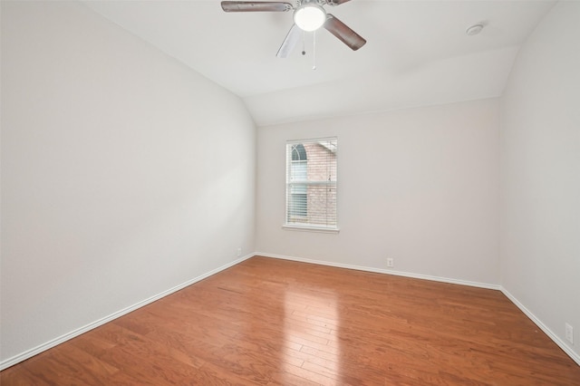 spare room with a ceiling fan, baseboards, vaulted ceiling, and wood finished floors