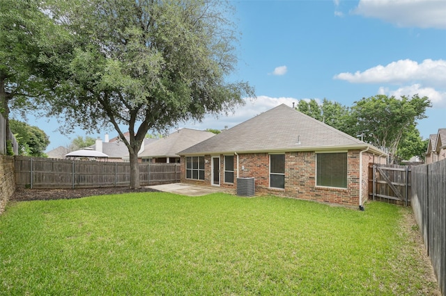 rear view of house featuring roof with shingles, brick siding, a fenced backyard, a patio, and a yard