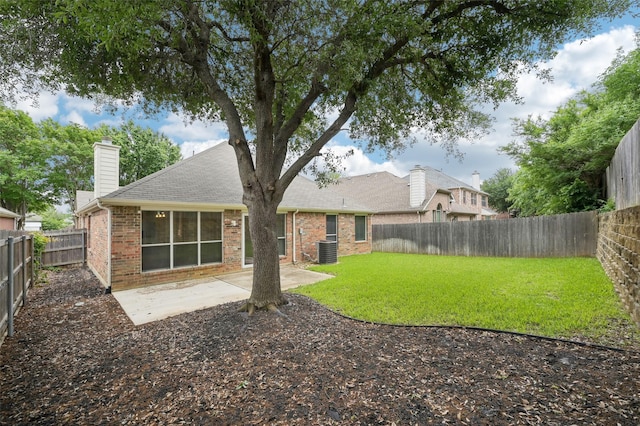 rear view of property featuring a chimney, brick siding, central AC, a fenced backyard, and a patio
