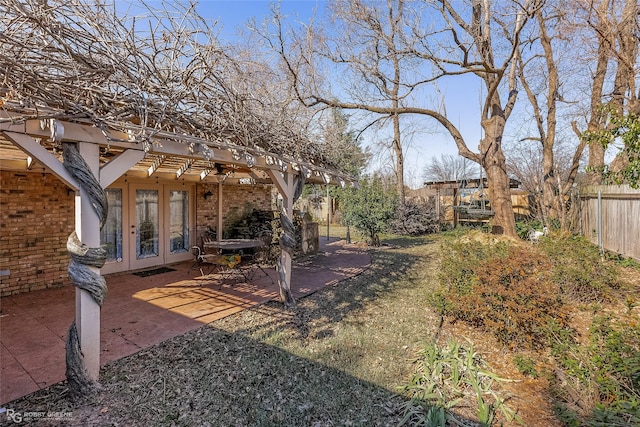 view of yard with a patio, fence, and french doors