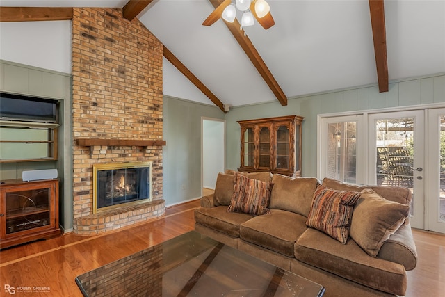 living area featuring ceiling fan, lofted ceiling with beams, wood finished floors, and a fireplace