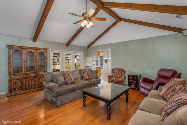 living room with vaulted ceiling with beams, ceiling fan, and light wood-style flooring