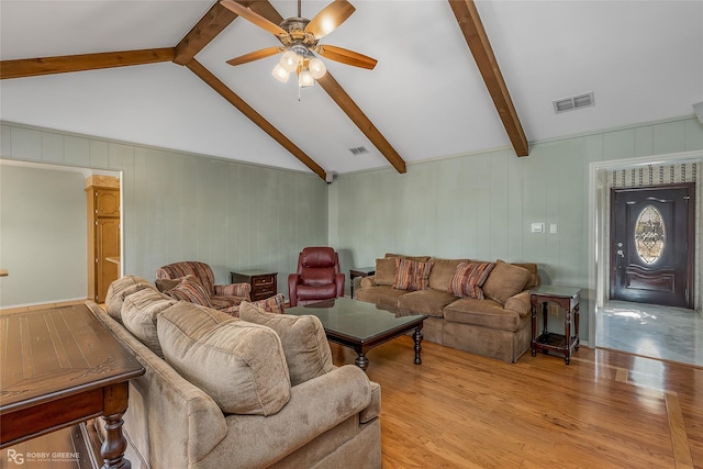 living area with light wood-style floors, vaulted ceiling with beams, ceiling fan, and visible vents