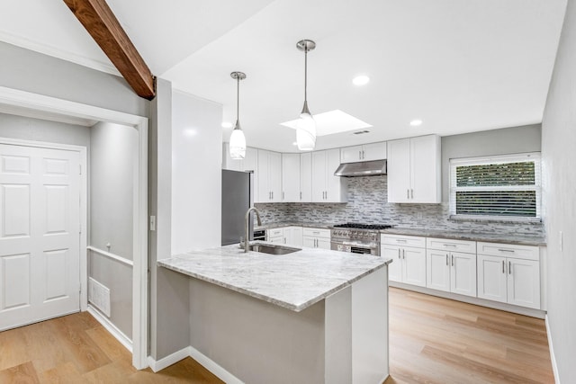 kitchen with white cabinetry, a sink, a peninsula, under cabinet range hood, and light wood-style flooring