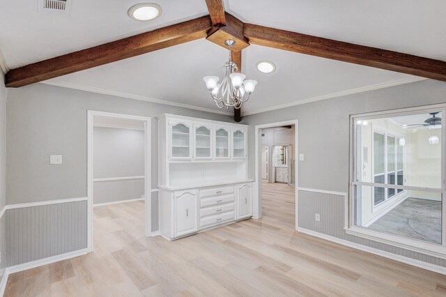 unfurnished dining area with visible vents, ornamental molding, wainscoting, light wood-style floors, and vaulted ceiling with beams
