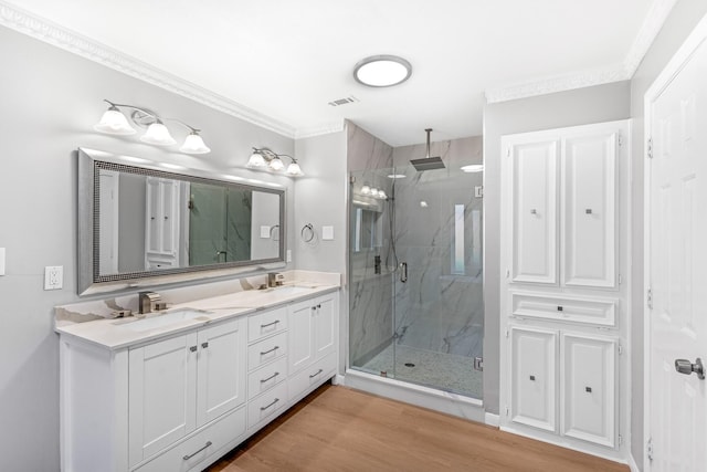 full bath with visible vents, a sink, a marble finish shower, and ornamental molding
