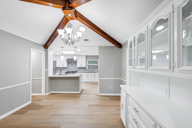 kitchen featuring white cabinets, a chandelier, backsplash, light wood-type flooring, and under cabinet range hood
