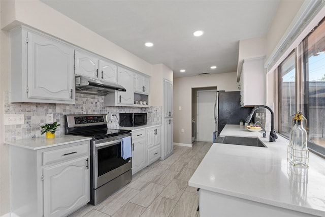 kitchen featuring black microwave, under cabinet range hood, stainless steel electric stove, tasteful backsplash, and a sink