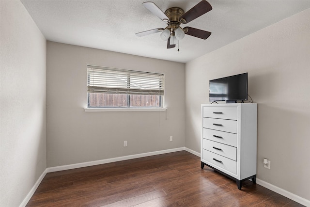 unfurnished bedroom with dark wood-type flooring, a ceiling fan, and baseboards