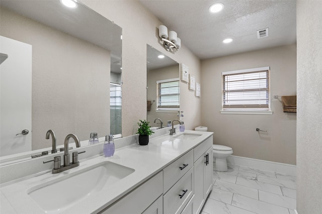 bathroom with a sink, toilet, double vanity, and marble finish floor