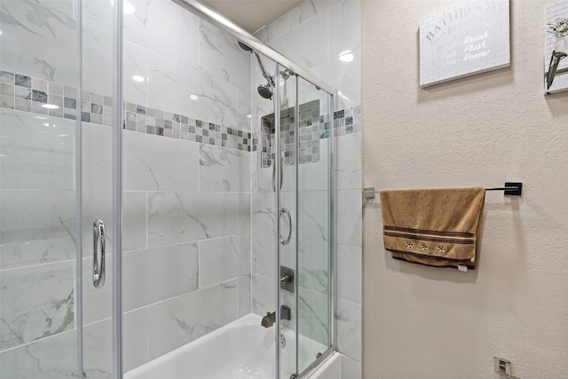 full bath with a textured wall and combined bath / shower with glass door