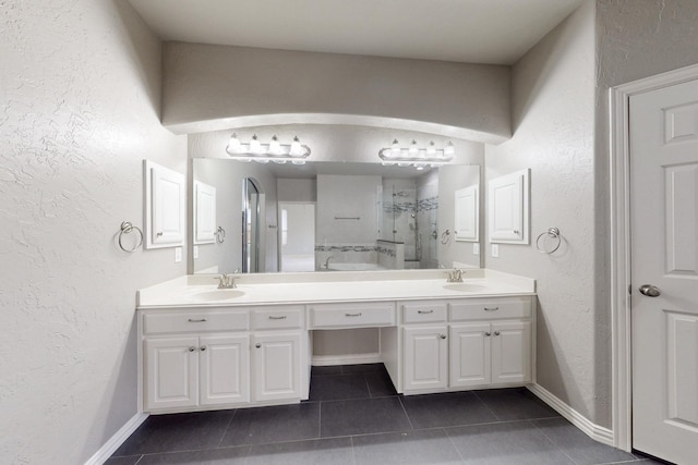 full bath featuring a textured wall, a tile shower, a sink, and tile patterned floors