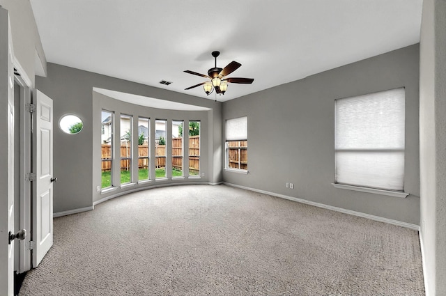 carpeted spare room featuring a ceiling fan, baseboards, and visible vents