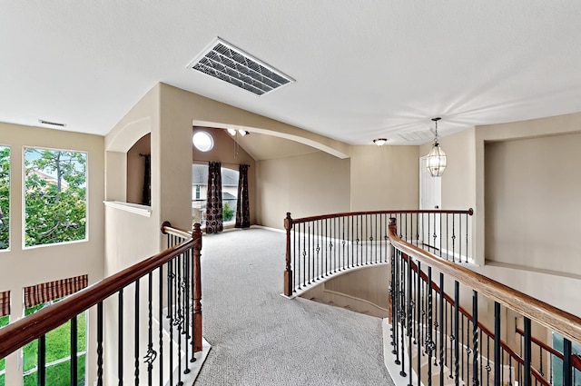 hallway featuring visible vents, carpet, lofted ceiling, and an upstairs landing