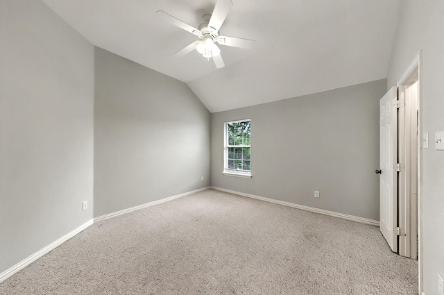empty room featuring a ceiling fan, light colored carpet, vaulted ceiling, and baseboards