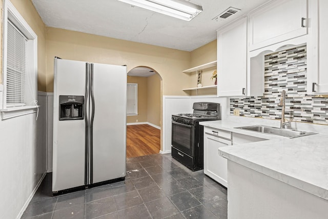 4416 Surrey St, Fort Worth, TX 76133 - kitchen featuring white refrigerator with ice dispenser, black gas range, arched walkways, open shelves, and white cabinetry