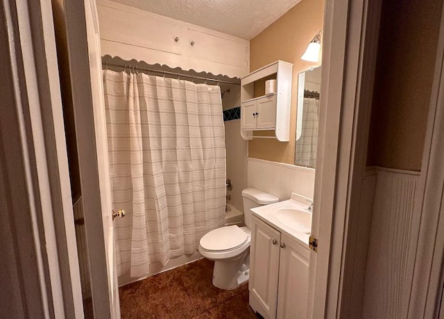 full bath with a textured ceiling, wainscoting, shower / tub combo, vanity, and toilet