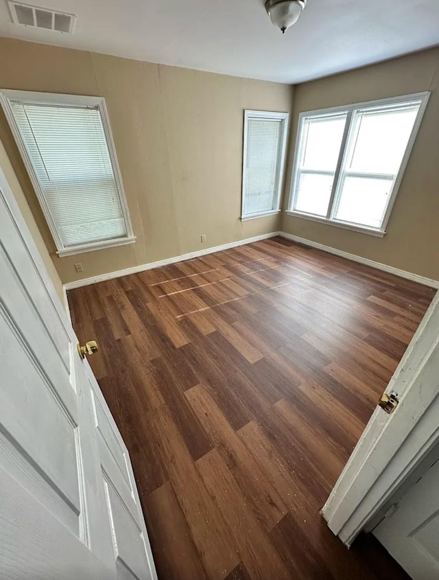 spare room featuring baseboards, wood finished floors, and visible vents