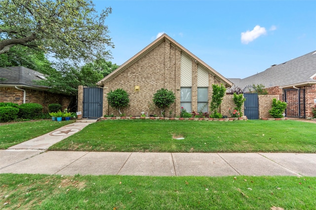 view of front of house with brick siding, a gate, and a front yard