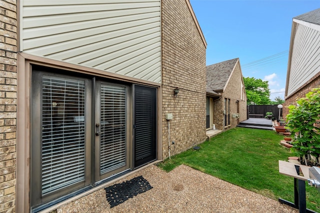 exterior space featuring brick siding, fence, a yard, and a deck