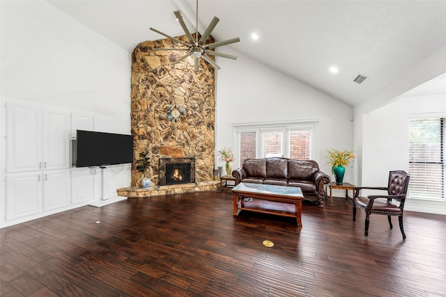 living area featuring high vaulted ceiling, ceiling fan, a stone fireplace, and wood finished floors