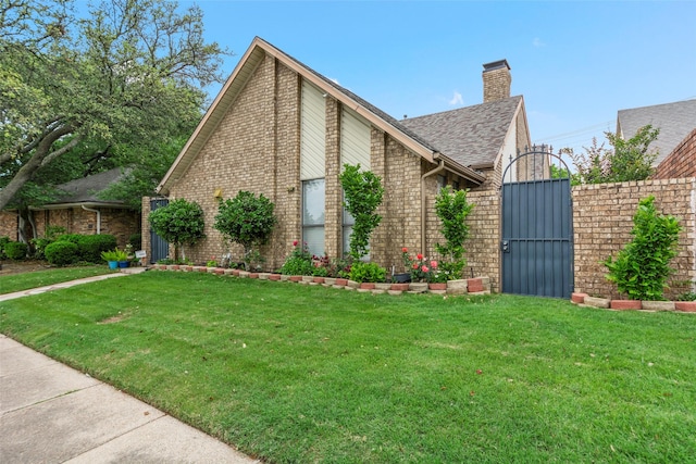 view of home's exterior with a yard, brick siding, a chimney, and a gate