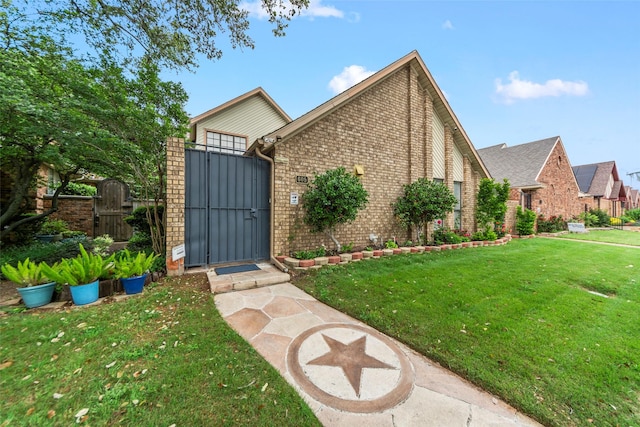 view of front of home featuring fence, a gate, a front lawn, and brick siding