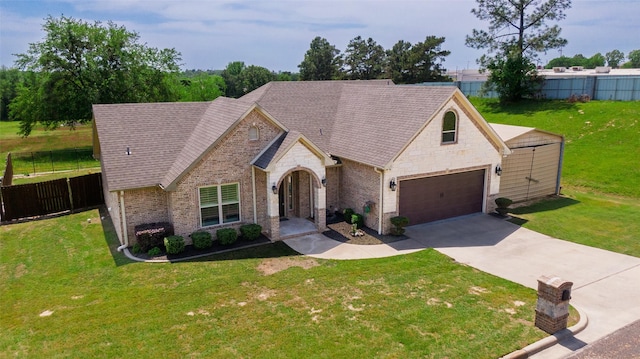 french country home featuring a front yard, fence, driveway, and stone siding