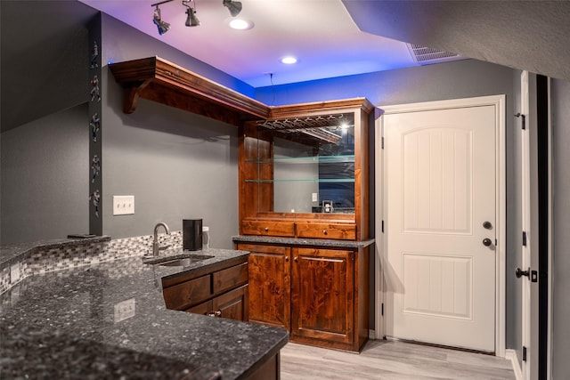 bar featuring light wood-style floors, a sink, and visible vents