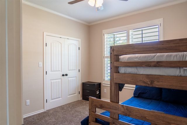 bedroom with ceiling fan, carpet floors, baseboards, ornamental molding, and a closet