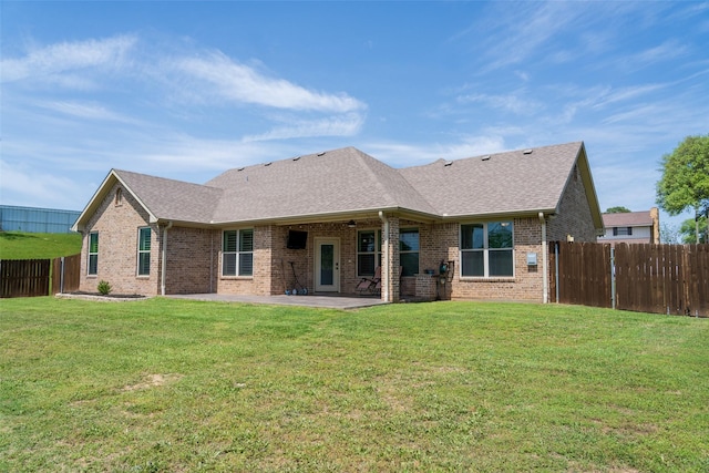 rear view of house featuring brick siding, a patio, a yard, and a fenced backyard