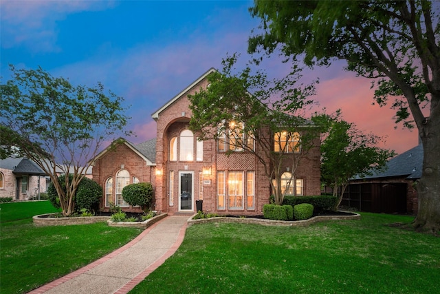 traditional-style home featuring brick siding and a front yard
