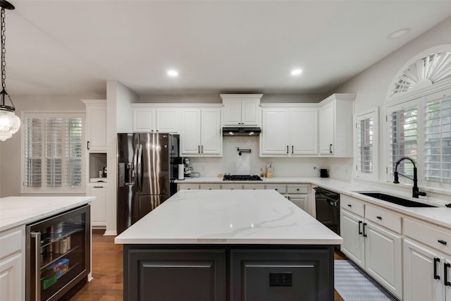 kitchen with beverage cooler, under cabinet range hood, white cabinets, a sink, and black appliances