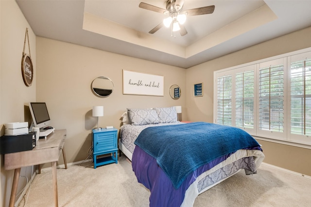 carpeted bedroom featuring baseboards, ceiling fan, and a tray ceiling