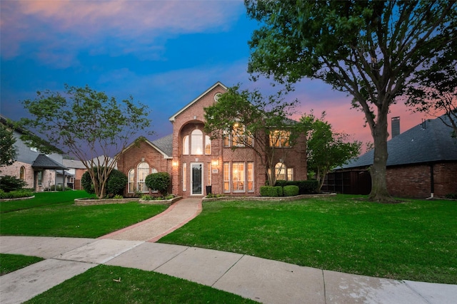 traditional home with brick siding and a front lawn