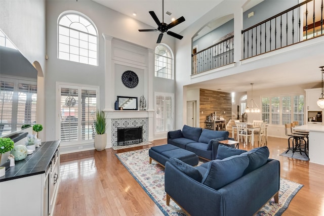 living area with plenty of natural light, a high ceiling, a fireplace, and ceiling fan with notable chandelier