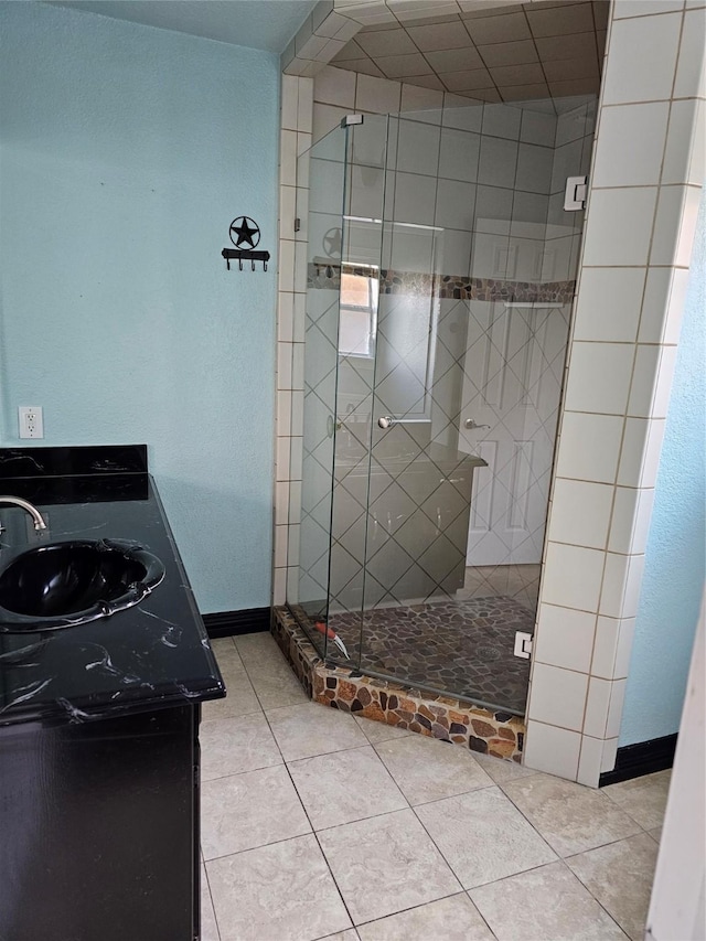 full bath featuring vanity, baseboards, tile patterned flooring, and a stall shower