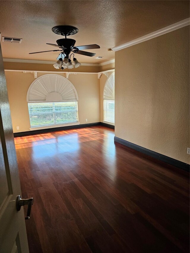 empty room with ceiling fan, a textured ceiling, crown molding, wood finished floors, and baseboards