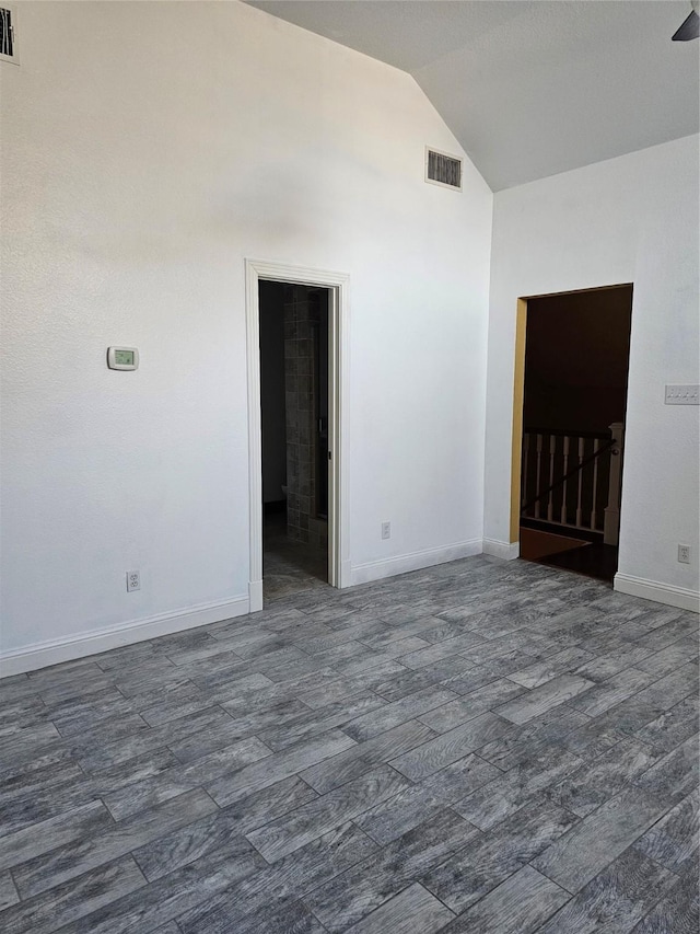 unfurnished room with baseboards, visible vents, and vaulted ceiling